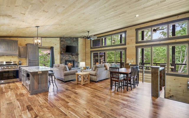 interior space with a fireplace, high vaulted ceiling, wood ceiling, and an inviting chandelier