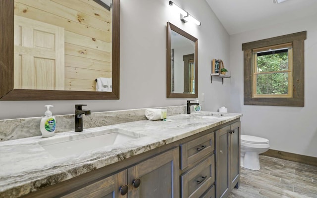 bathroom featuring hardwood / wood-style floors, vanity, lofted ceiling, and toilet