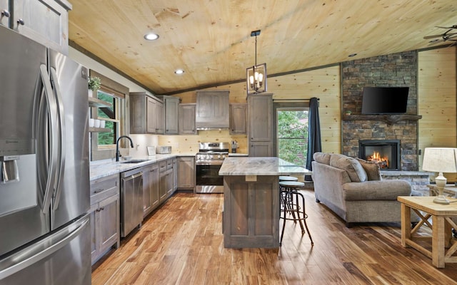 kitchen featuring wood walls, pendant lighting, stainless steel appliances, and wooden ceiling