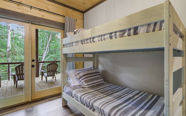 bedroom featuring hardwood / wood-style flooring, wooden walls, access to outside, and french doors