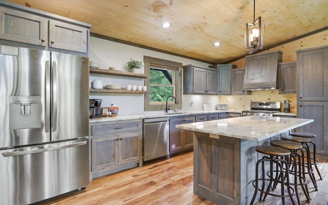 kitchen featuring pendant lighting, a center island, stainless steel appliances, and vaulted ceiling