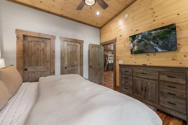 bedroom featuring ceiling fan, wooden ceiling, dark hardwood / wood-style flooring, lofted ceiling, and wooden walls