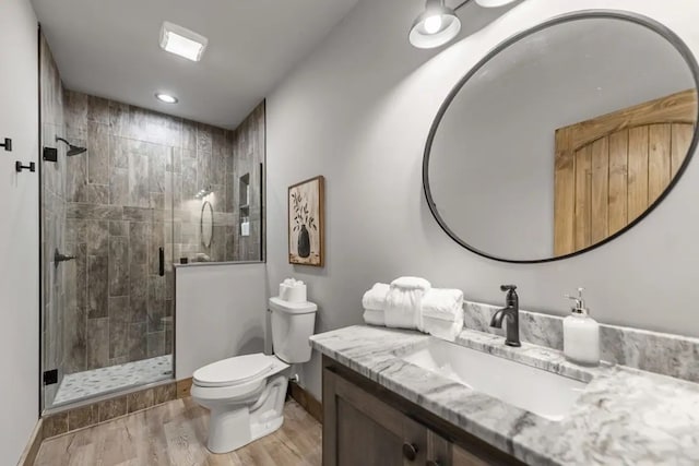 bathroom with wood-type flooring, vanity, toilet, and a shower with door