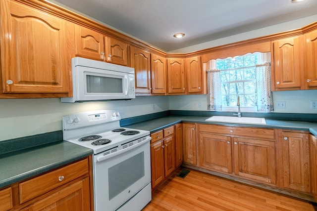 kitchen featuring sink, white appliances, and light wood-type flooring