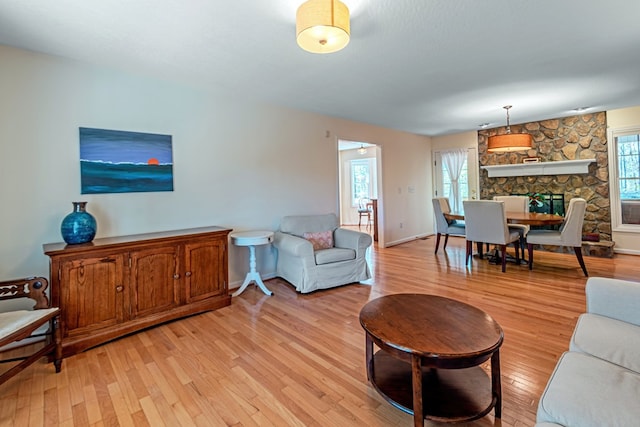 living room featuring a stone fireplace and light hardwood / wood-style flooring