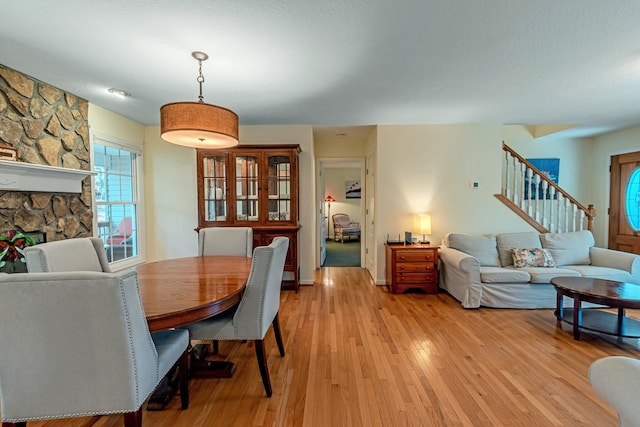 dining room featuring light hardwood / wood-style floors and a stone fireplace