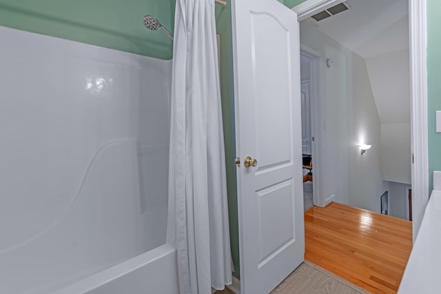 bathroom featuring shower / bath combo with shower curtain, hardwood / wood-style floors, and lofted ceiling