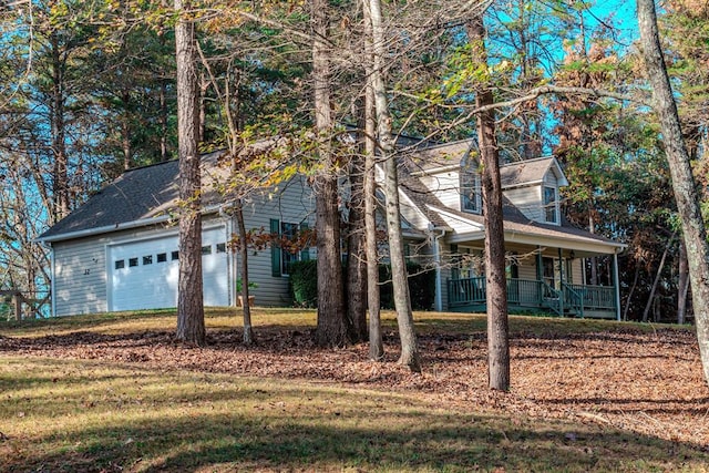 view of front of property with covered porch, a front yard, and a garage