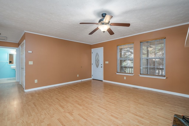 spare room featuring crown molding, a textured ceiling, and light wood-type flooring