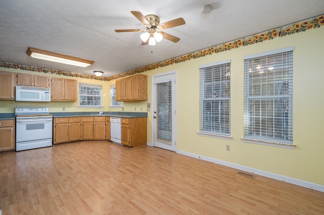 kitchen with a textured ceiling, white appliances, light hardwood / wood-style floors, and sink