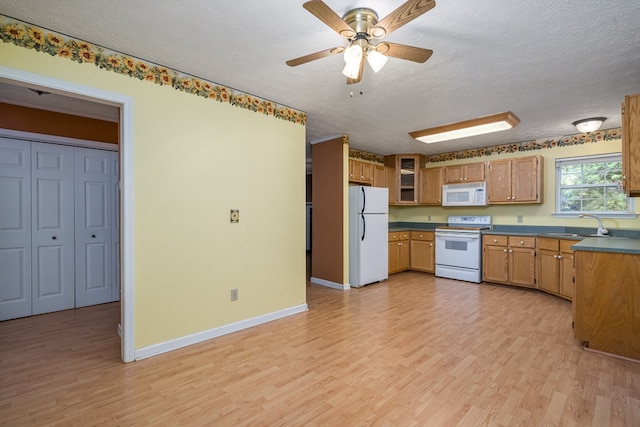 kitchen featuring light wood-type flooring, a textured ceiling, and white appliances