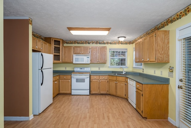 kitchen featuring a textured ceiling, light hardwood / wood-style floors, white appliances, and sink