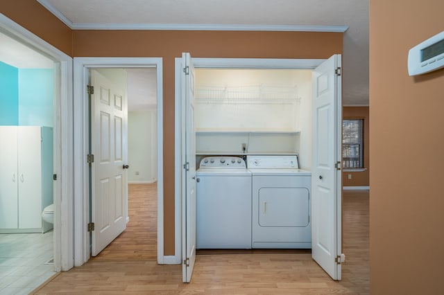 laundry area with a textured ceiling, independent washer and dryer, light wood-type flooring, and crown molding