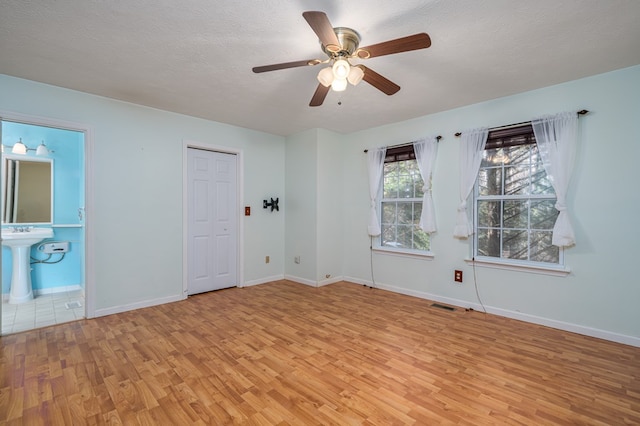 unfurnished room with ceiling fan, a textured ceiling, and light wood-type flooring