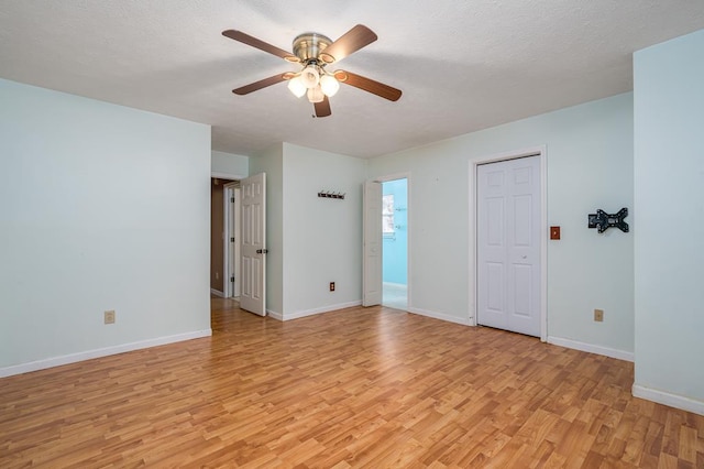 unfurnished room with ceiling fan, light wood-type flooring, and a textured ceiling