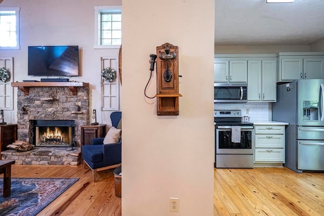 104 E Buck Run, Dahlonega, GA 30533 - kitchen featuring stainless steel appliances, light wood-style floors, a fireplace, backsplash, and open floor plan
