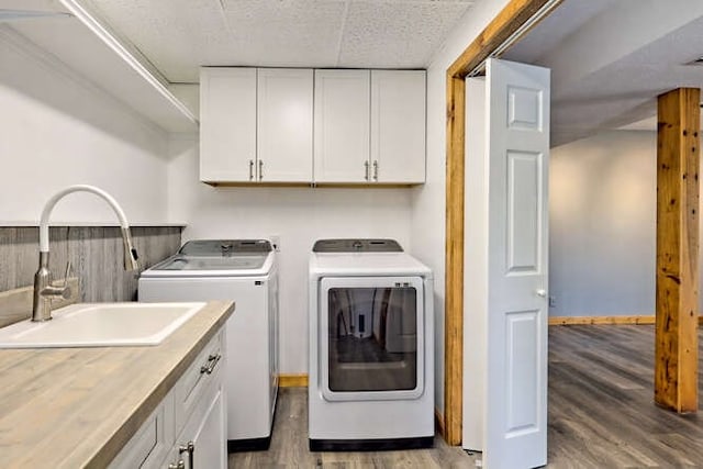 clothes washing area with cabinets, dark hardwood / wood-style floors, sink, and washing machine and clothes dryer