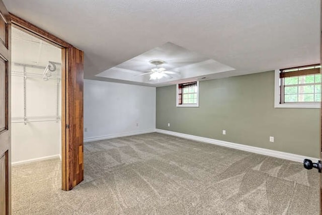 basement featuring light carpet, ceiling fan, and a healthy amount of sunlight