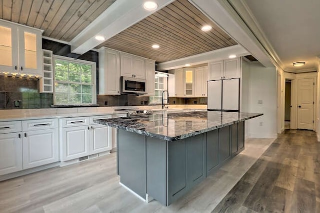 kitchen featuring dark stone countertops, white cabinets, white refrigerator, and tasteful backsplash