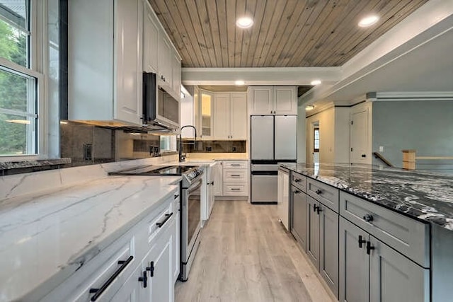 kitchen featuring light stone counters, appliances with stainless steel finishes, light wood-type flooring, and decorative backsplash