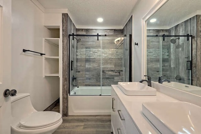 full bathroom featuring vanity, a textured ceiling, shower / bath combination with glass door, hardwood / wood-style flooring, and toilet