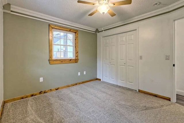 unfurnished bedroom featuring carpet, a textured ceiling, ceiling fan, and crown molding