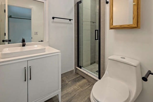 bathroom featuring hardwood / wood-style floors, vanity, toilet, and a shower with shower door