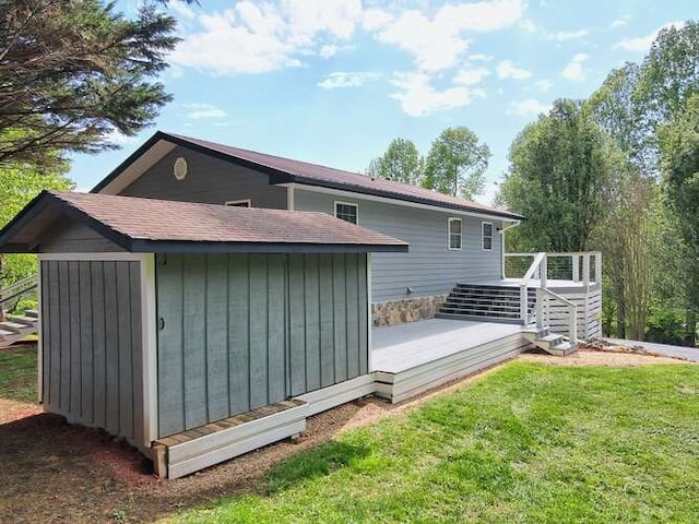 back of house featuring a lawn, a deck, and a storage unit