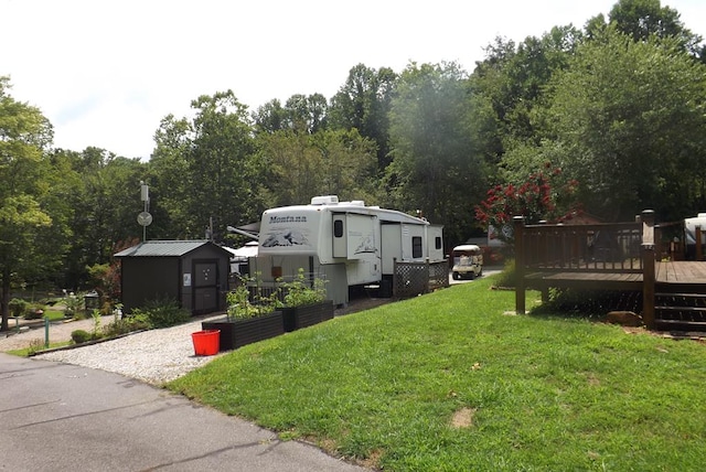 view of side of property with a storage unit, a yard, and a deck