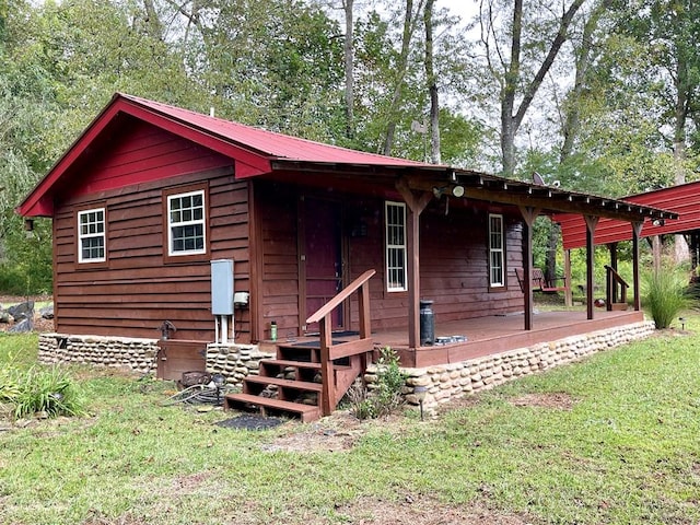 back of house with metal roof and a yard