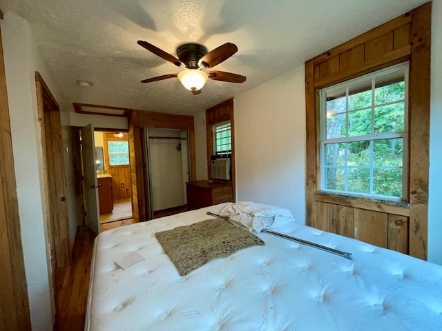 unfurnished bedroom with wooden walls, a closet, a ceiling fan, and wood finished floors