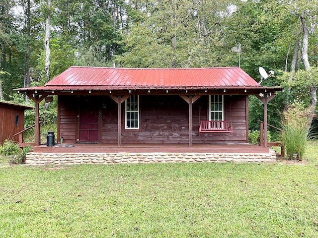 back of property featuring a wooded view, metal roof, and a lawn