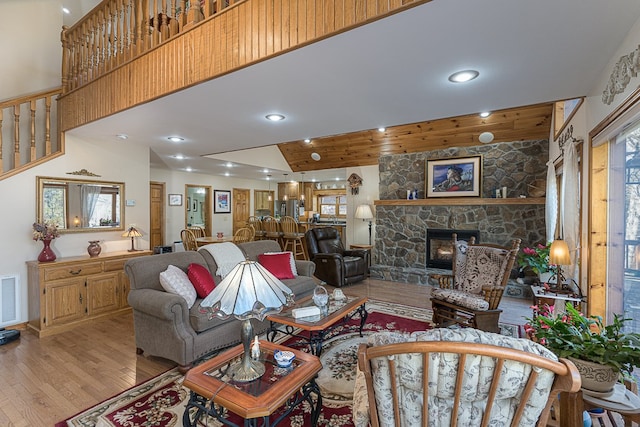 living room featuring a fireplace, high vaulted ceiling, and light wood-type flooring