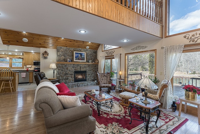 living room with light hardwood / wood-style flooring, a fireplace, a wealth of natural light, and a high ceiling