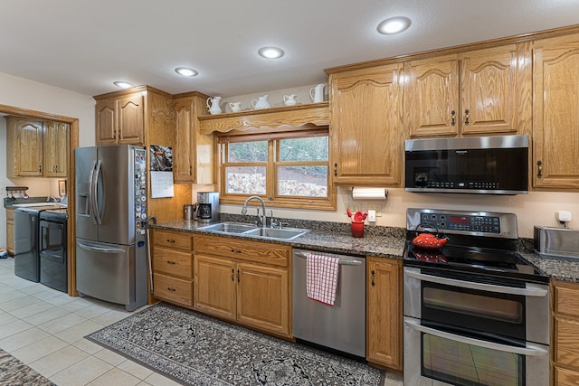 kitchen with dark stone countertops, sink, light tile patterned flooring, and appliances with stainless steel finishes