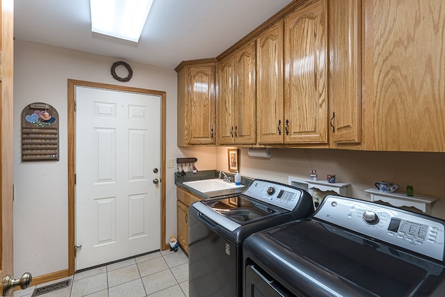 laundry area with cabinets, washing machine and clothes dryer, sink, and light tile patterned floors