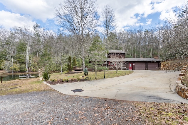 view of front facade featuring a garage, a water view, and a front lawn