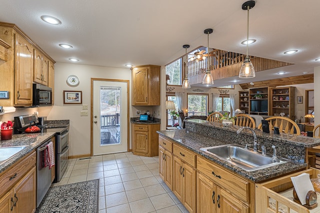 kitchen featuring a kitchen bar, sink, hanging light fixtures, light tile patterned floors, and stainless steel appliances