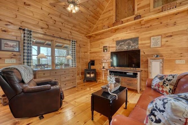 271 Kates Cove Rd, Murphy, NC 28906 - living room featuring a wood stove, a ceiling fan, wood walls, high vaulted ceiling, and hardwood / wood-style flooring