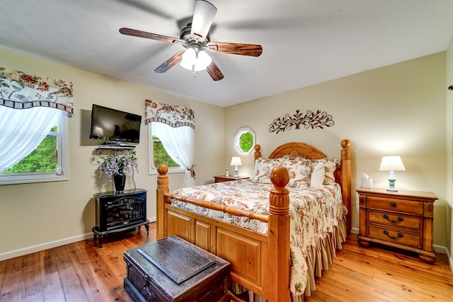 1504 Red Marble Rd, Andrews, NC 28901 - bedroom featuring a wood stove, light wood-type flooring, and a ceiling fan