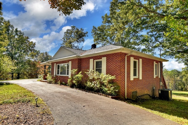 view of property exterior with central AC and a yard