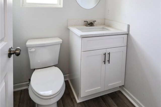 bathroom featuring toilet, vanity, wood finished floors, and baseboards
