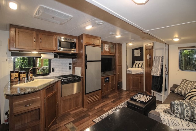 kitchen featuring tasteful backsplash, appliances with stainless steel finishes, sink, dark stone counters, and dark hardwood / wood-style floors