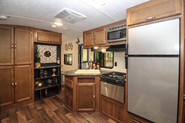 kitchen featuring tasteful backsplash, dark wood-type flooring, sink, stainless steel appliances, and ventilation hood