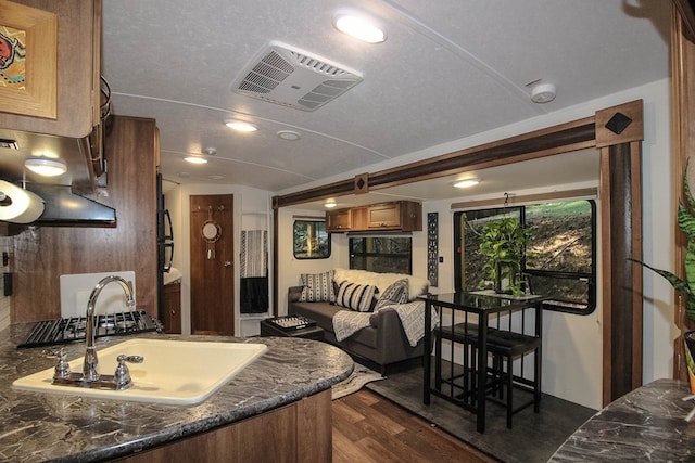 kitchen featuring sink, dark hardwood / wood-style floors, a textured ceiling, and dark stone counters