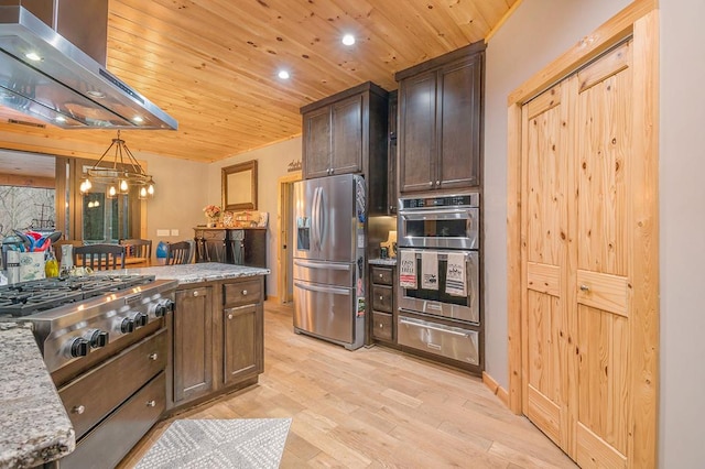 kitchen with light stone countertops, appliances with stainless steel finishes, ventilation hood, decorative light fixtures, and light hardwood / wood-style floors