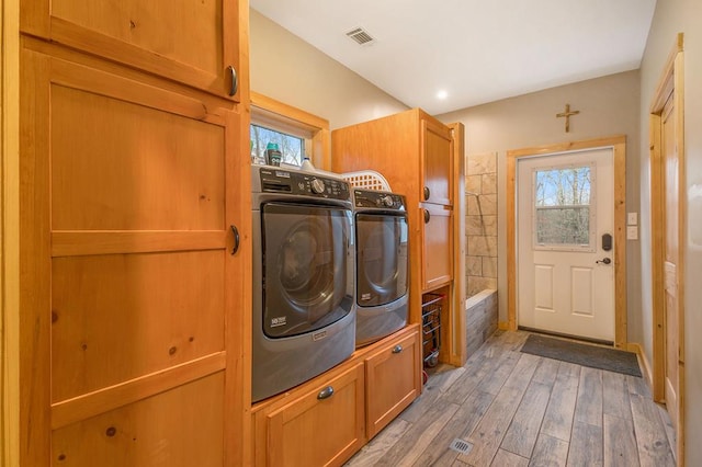 clothes washing area featuring cabinets, washer and clothes dryer, and wood-type flooring