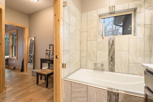 bathroom with hardwood / wood-style floors, vanity, and tiled shower / bath combo