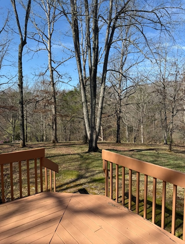 deck featuring a wooded view and a lawn