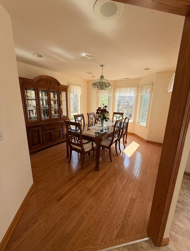 dining area with a wealth of natural light, a notable chandelier, light wood-style floors, and baseboards